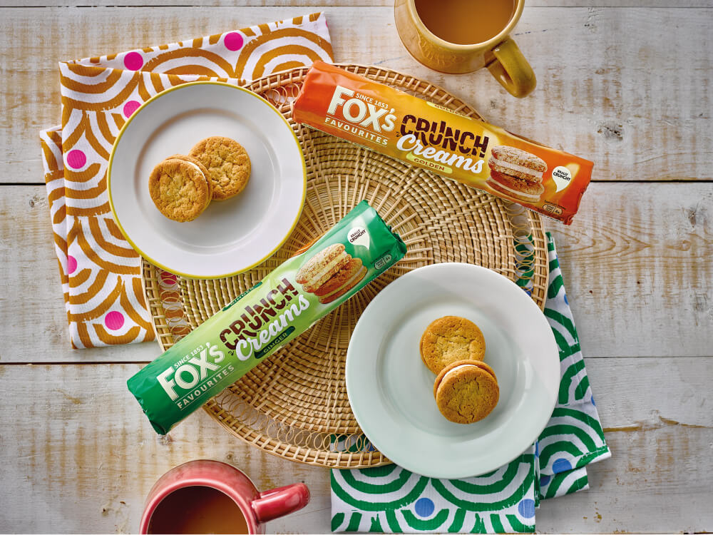 Packets of Crunch Cream biscuits with two plates of biscuits on a table