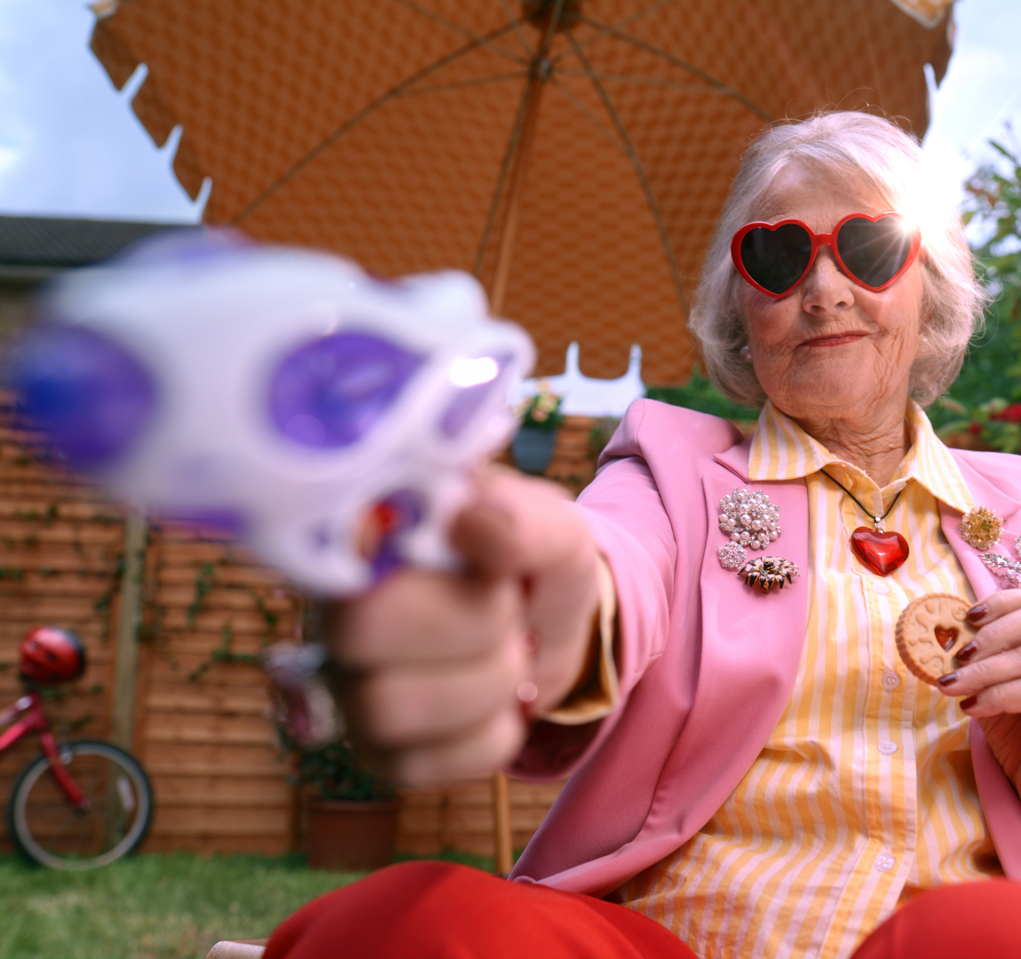 Senior woman with grey hair holding water pistol