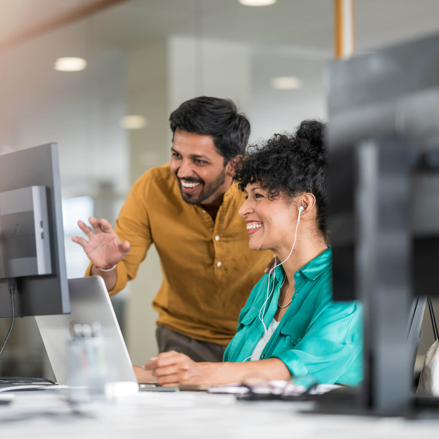 Two people laughing together looking at a computer screen