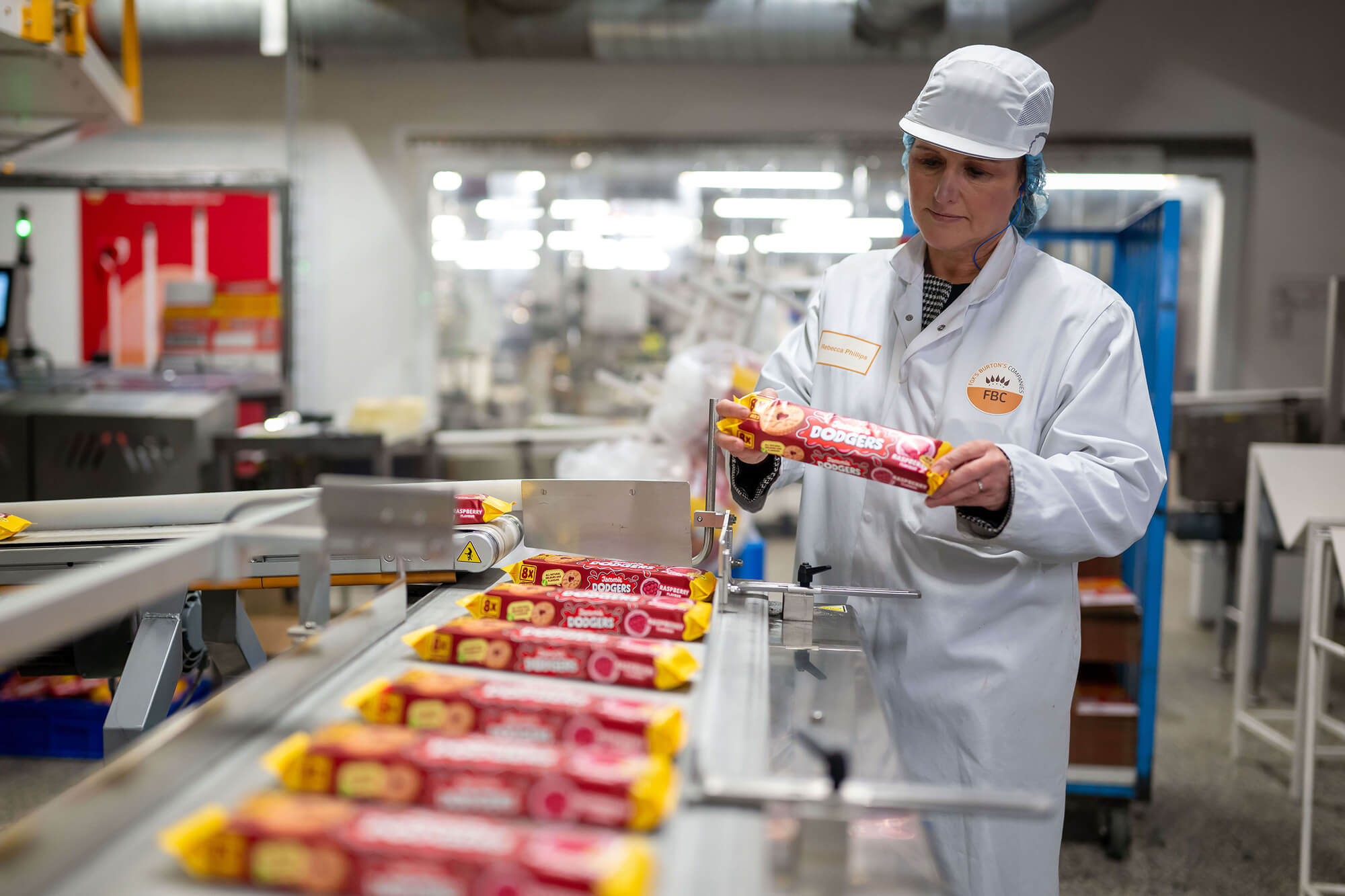 Female factory worker holding a packet of jammie dodgers