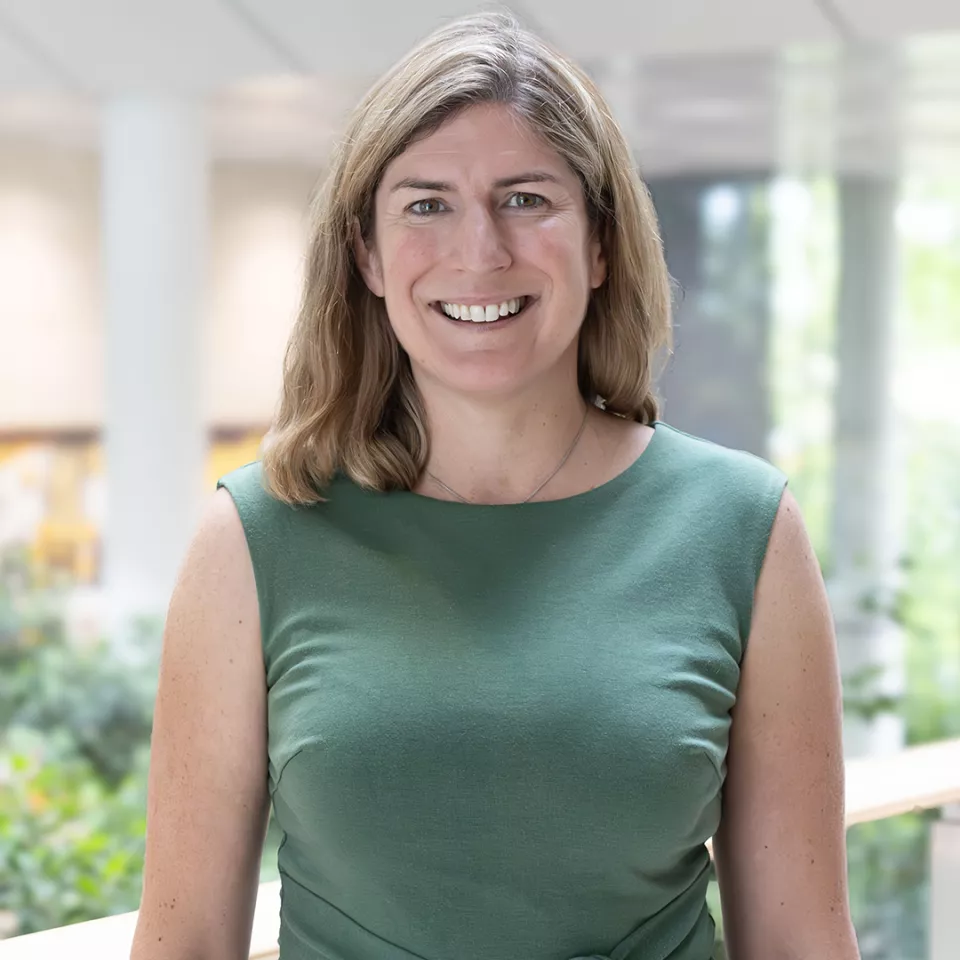 This shows a blonde haired female colleague of the UK&I smiling as she stands on the balcony in the office atrium
