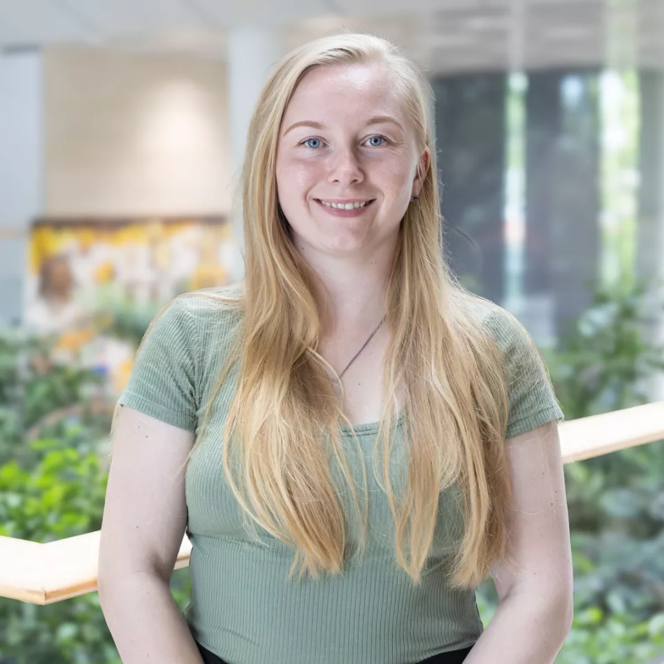 This shows a blonde haired female colleague of the UK&I smiling as she stands on the balcony in the office atrium