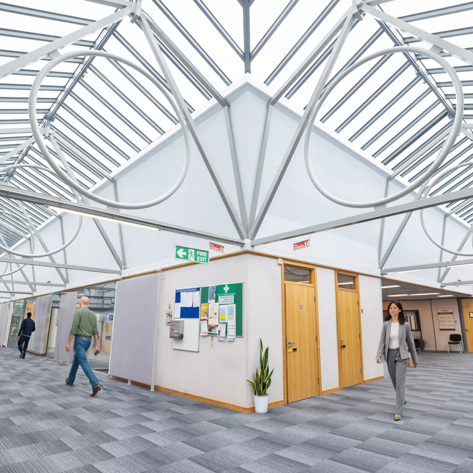 Open office area with a couple of people walking along 