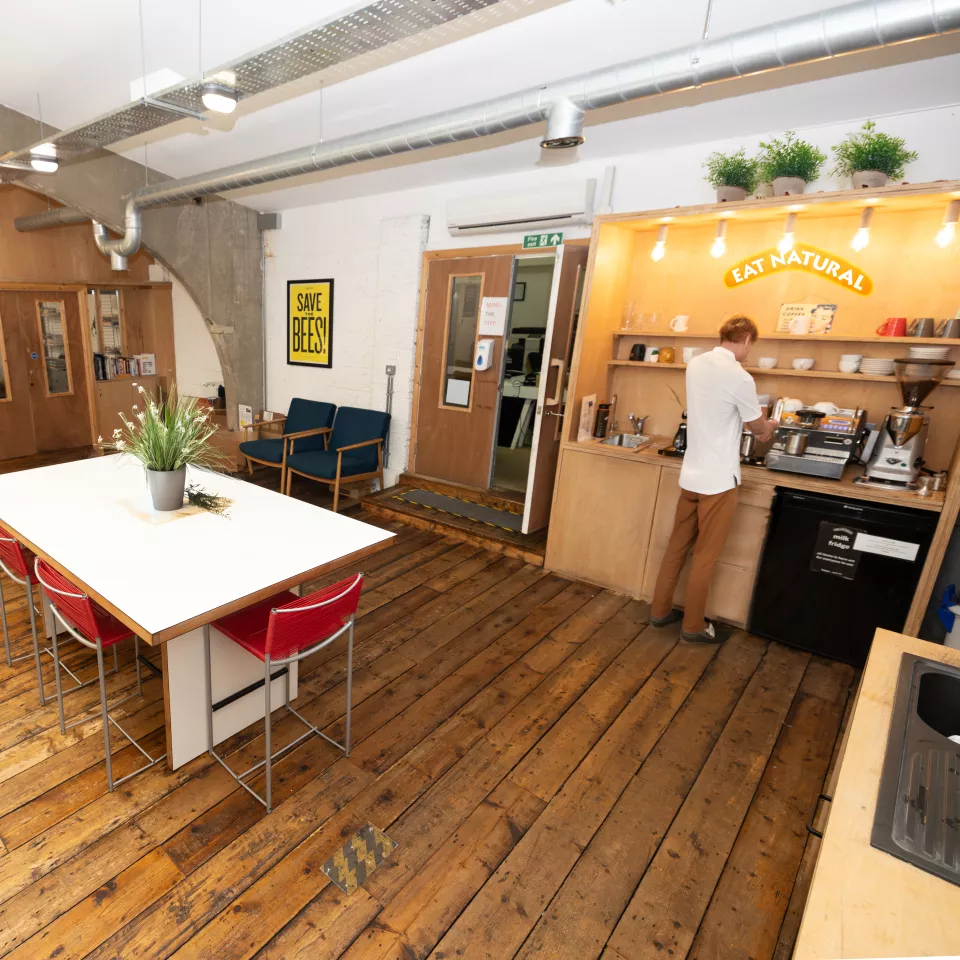Insdie the kitchen area within Halstead's office showing a man making a coffee 