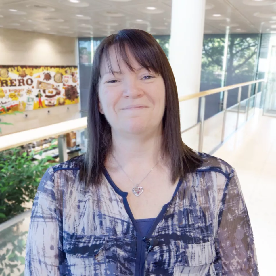 A female with dark hair standing in a elevated corridor 