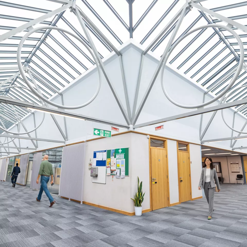 Open office area with a couple of people walking along the wide corridors 