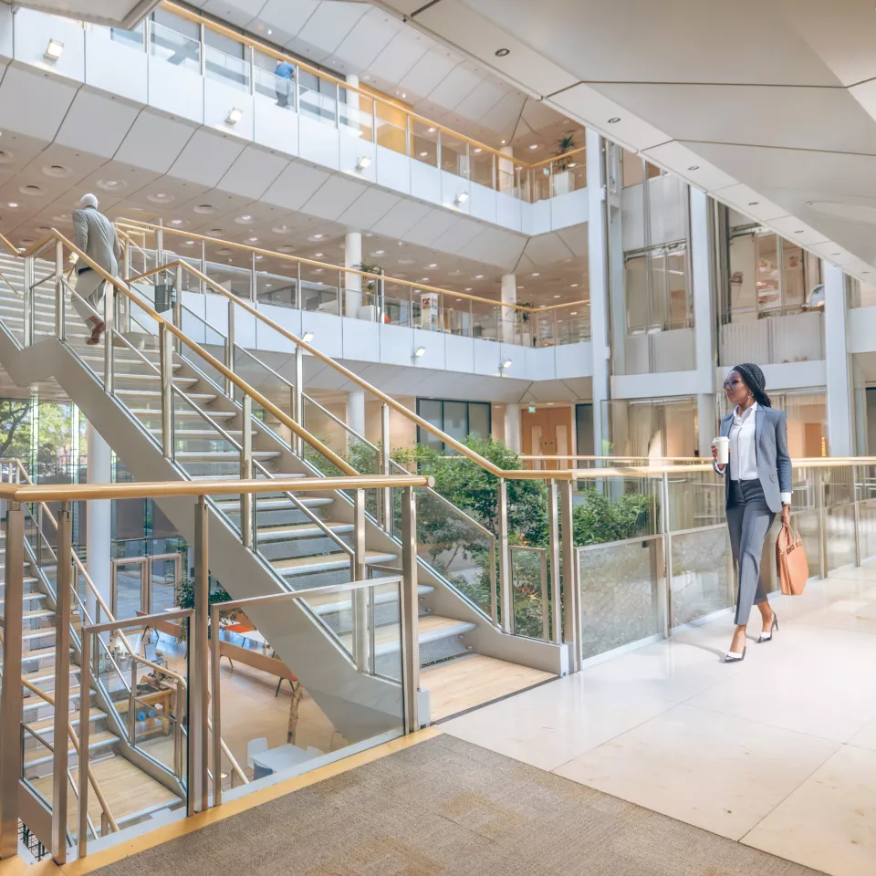 Open office area with a couple of people walking along in the atrium 