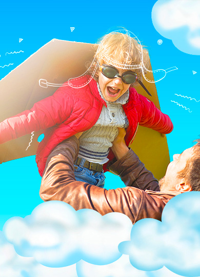 A father joyfully lifts a child dressed as an airplane pilot.