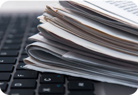 Stack of newspapers resting on a laptop keyboard
