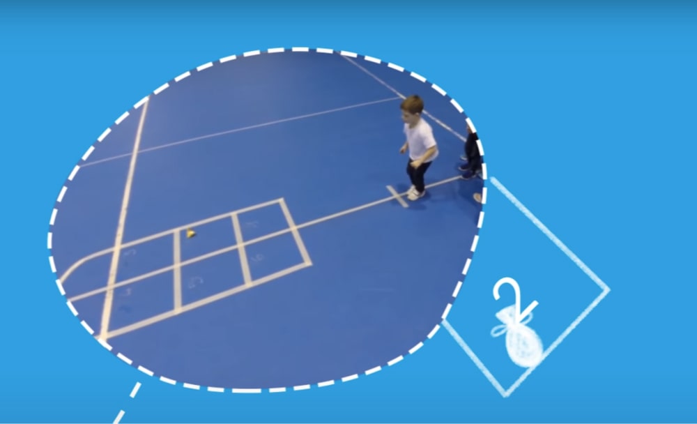 Boy playing hopscotch in a sports hall.