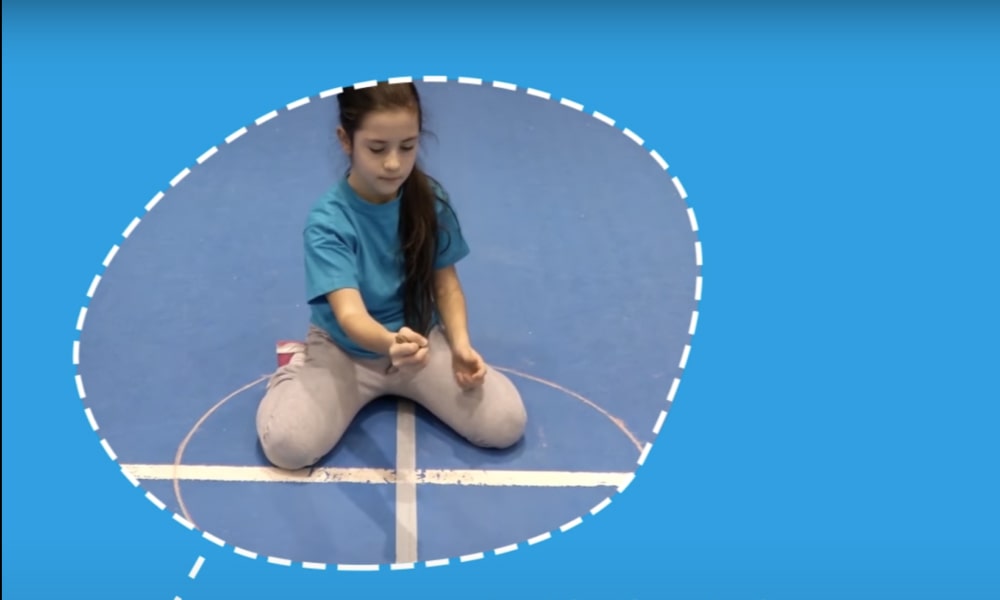 Girl sitting on the floor playing kernels in sports hall.