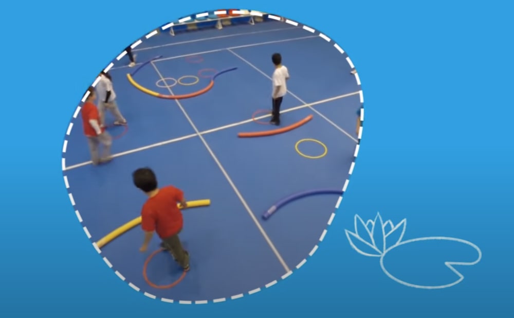Children playing memory game with coloured float noodles in sports hall.
