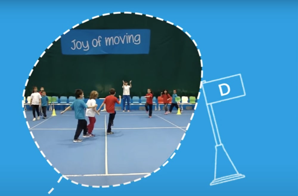 Children moving around in sports hall under teacher's instructions.