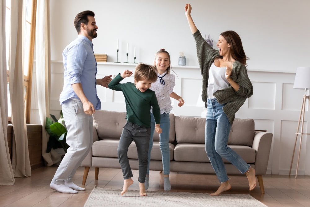 Parents and two children dancing in sitting room.