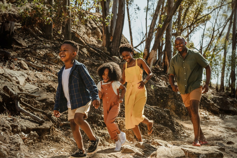 Parents and two children walking in forest.