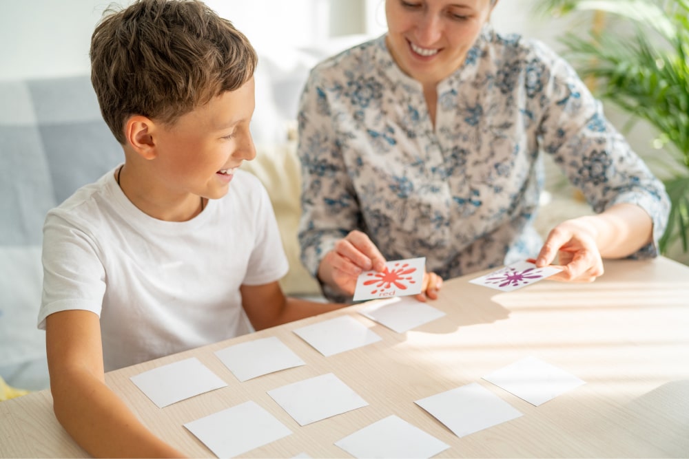 Boy plays memory board game with mother.