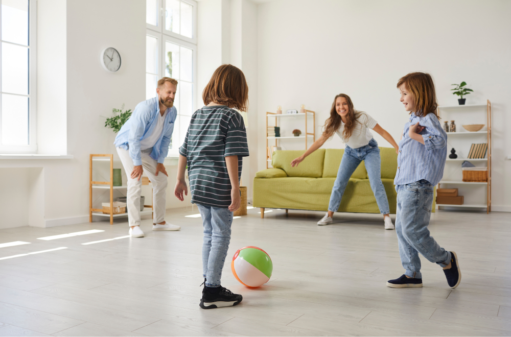 Two children playing with a ball with their parents in sitting room.