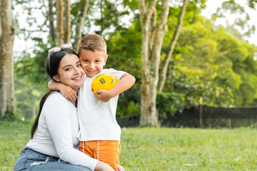 Child with ball hugging his mother