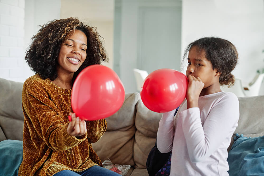 Woman and child blowing up balloons