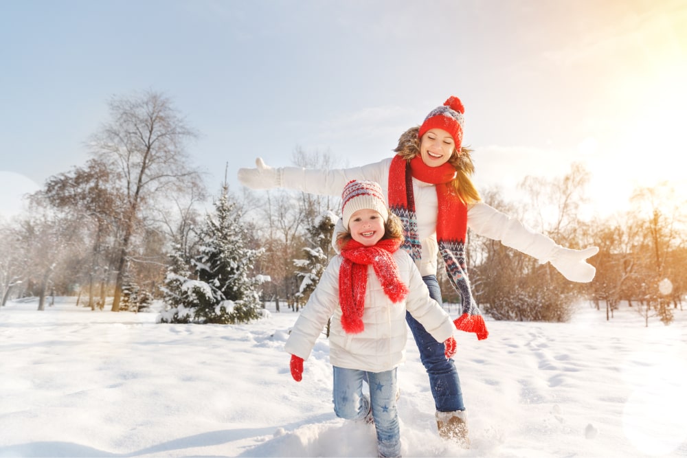 Mother and daughter smiling and running in snowscape.
