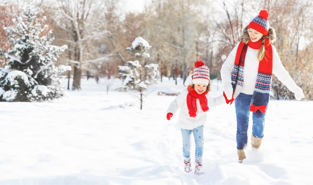 Mother and daughter smiling and walking in a snowscape.