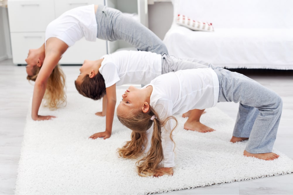 Woman and two children doing bridge stretch gymnastic exercises at home.
