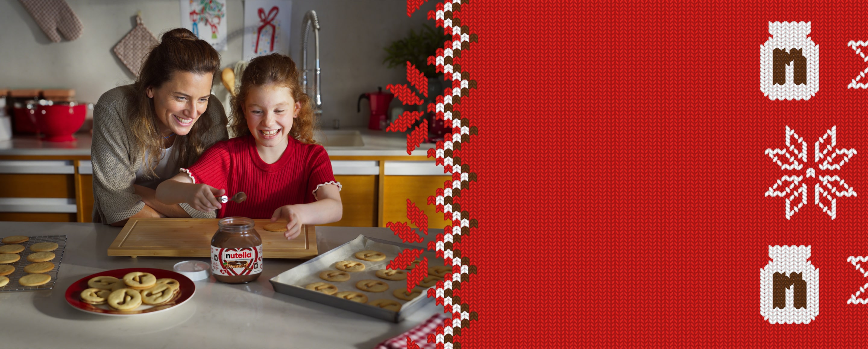 A young girl is using a spoon to scoop Nutella® out of a jar to decorate Nutella® biscuits, while her mother watches over her shoulder.